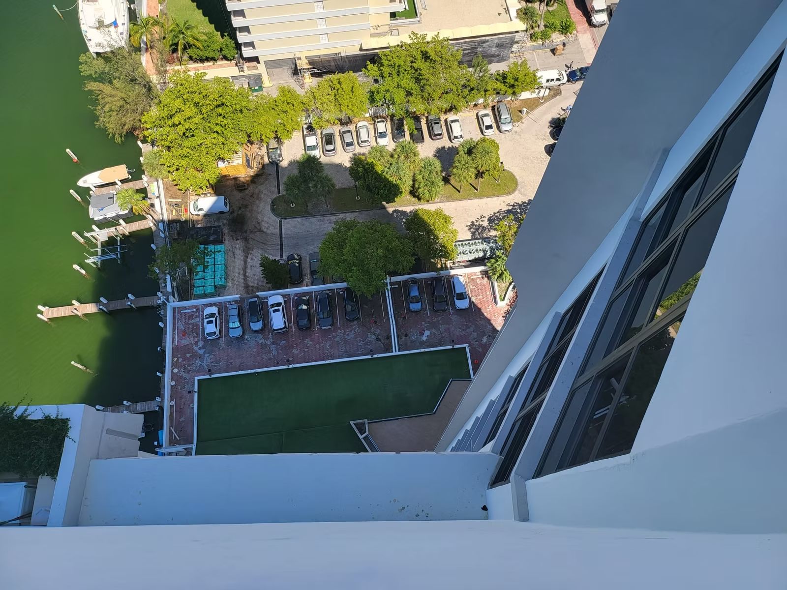 Looking down a condominium tower facade to parking, courts and landscaped grounds