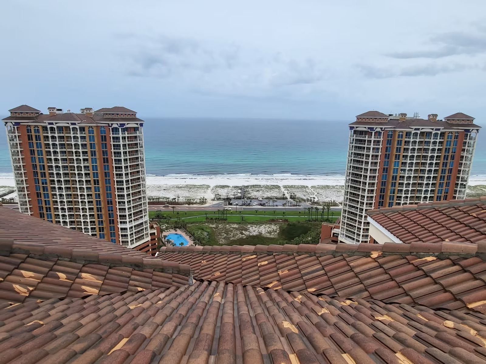 Clay tile roof in the foreground with twin oceanfront condominium towers behind