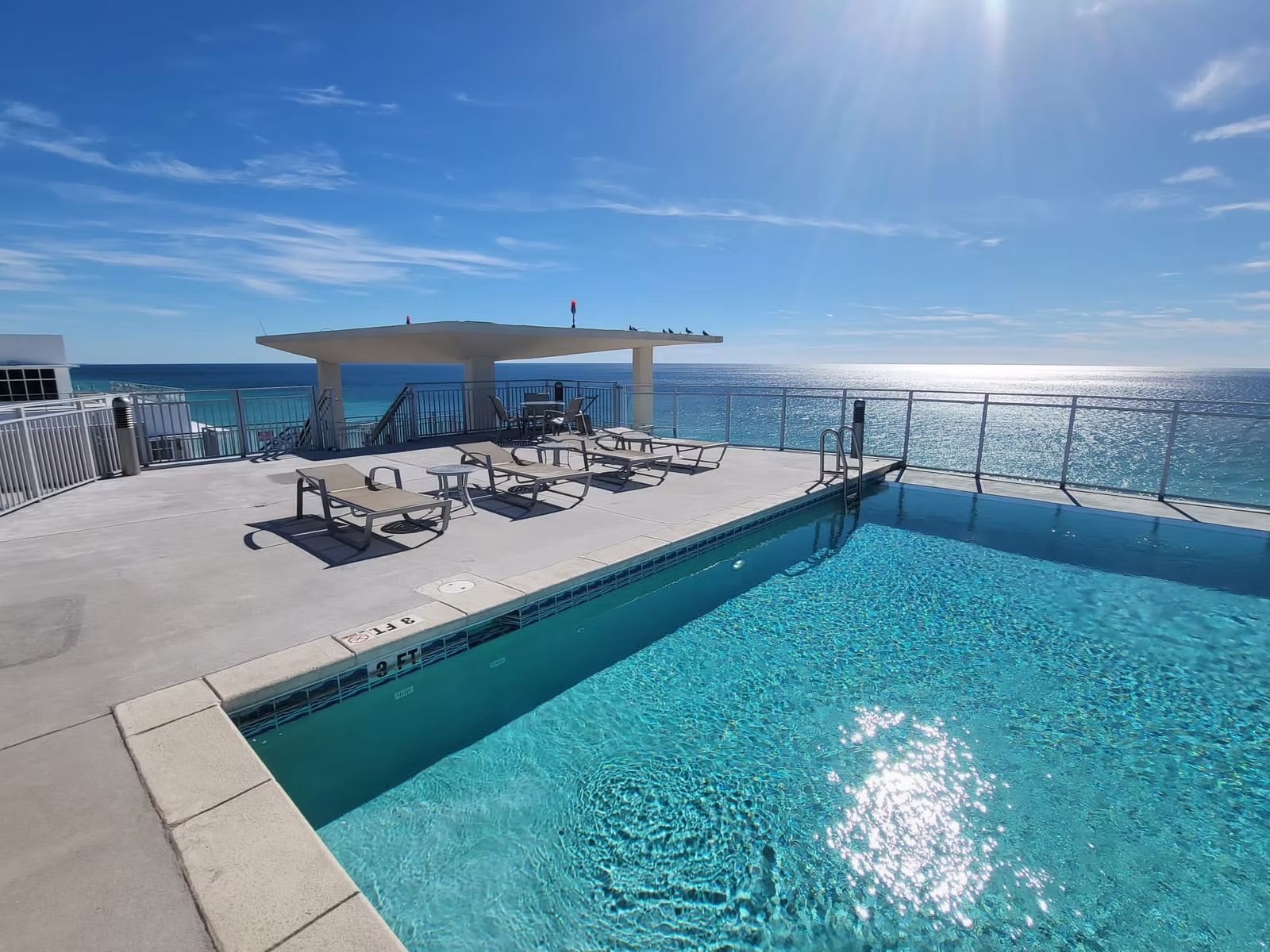 Rooftop pool and deck with lounge chairs overlooking the ocean