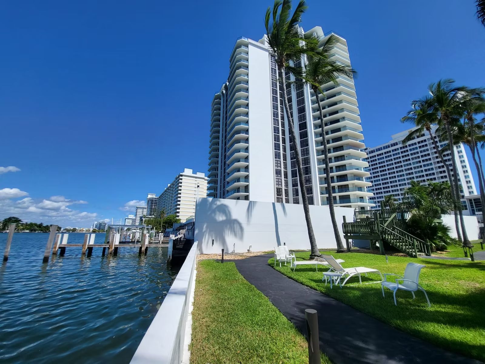 High-rise condominium beside a seawall and lawn on the bay