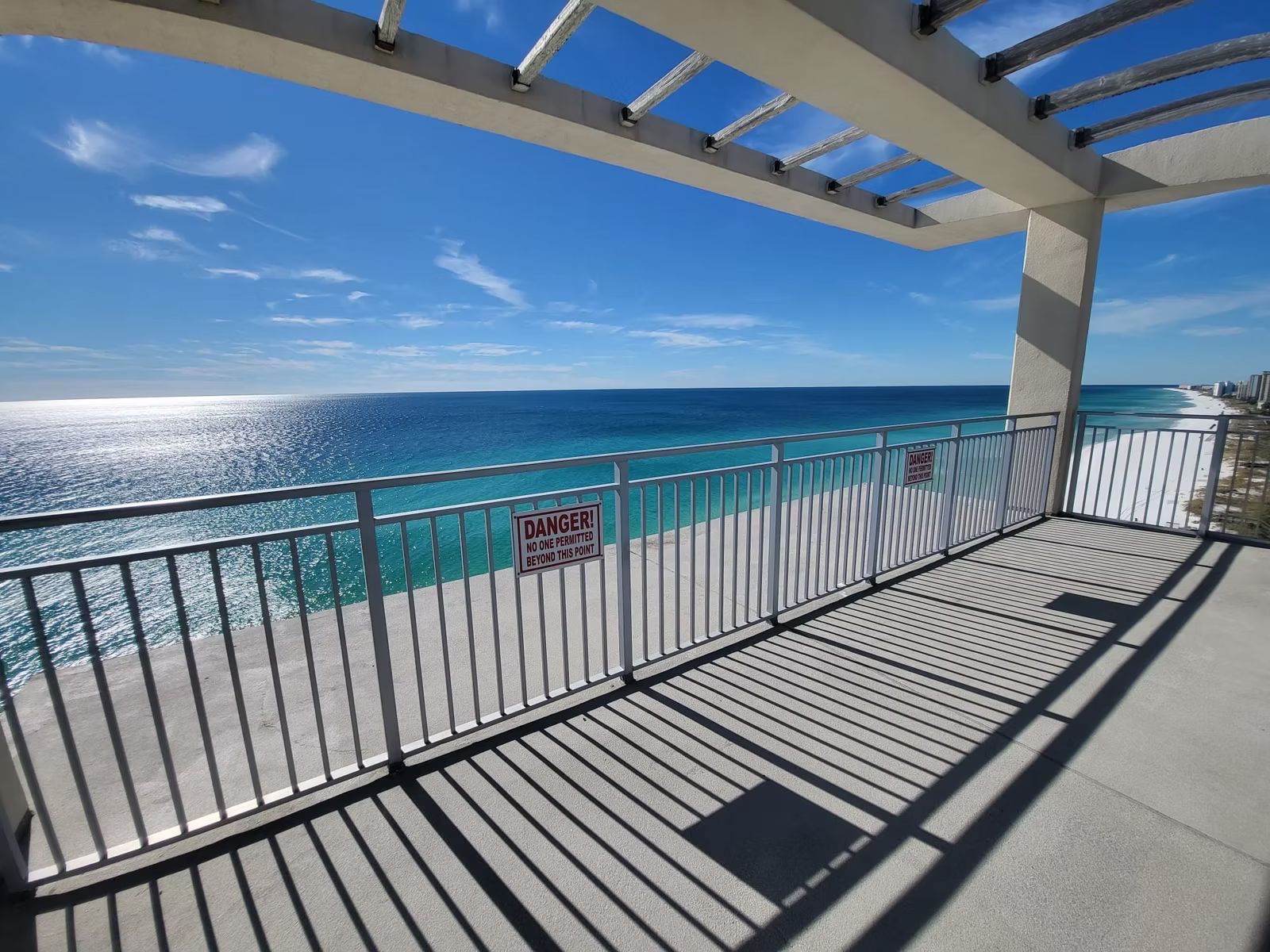 Beachfront terrace with aluminum railing and pergola overlooking the ocean